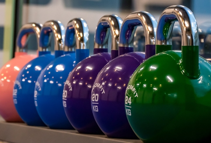Eine Reihe bunter Kettlebells in einem Fitnessstudio.