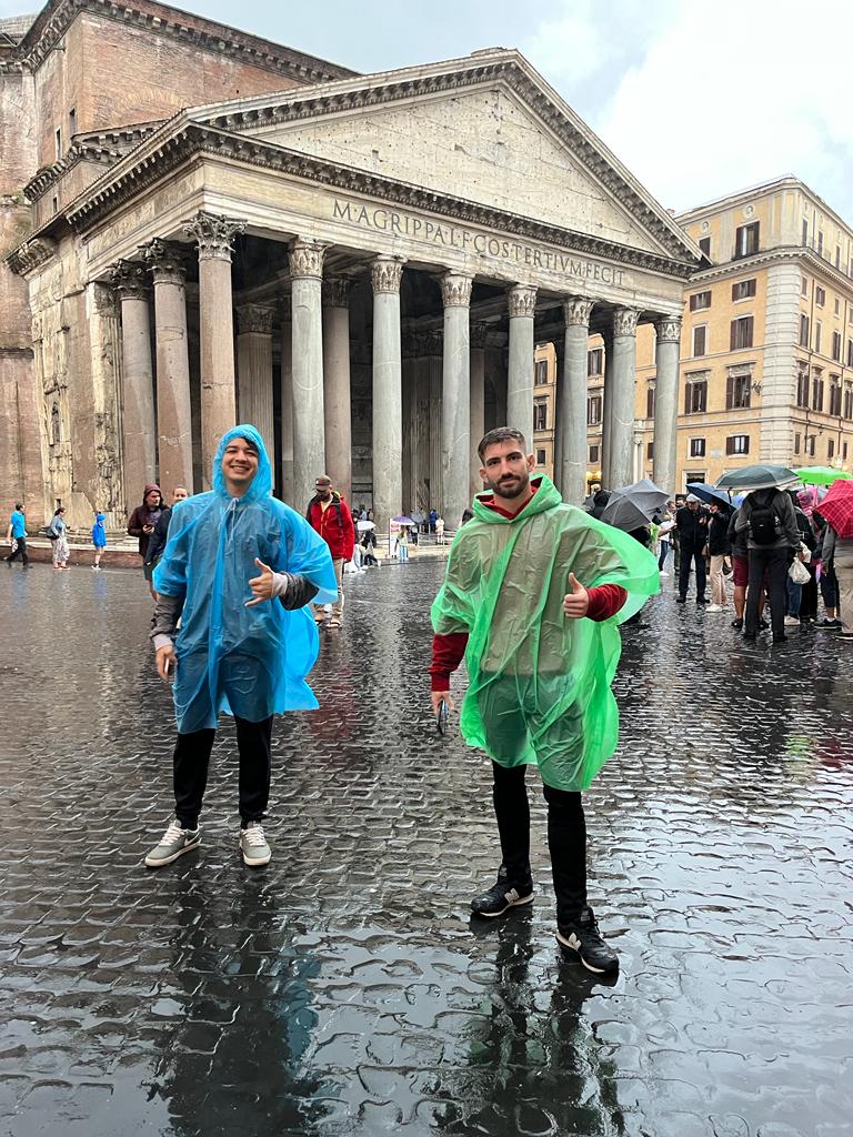 Zwei Männer in Regenmänteln stehen vor dem Pantheon.