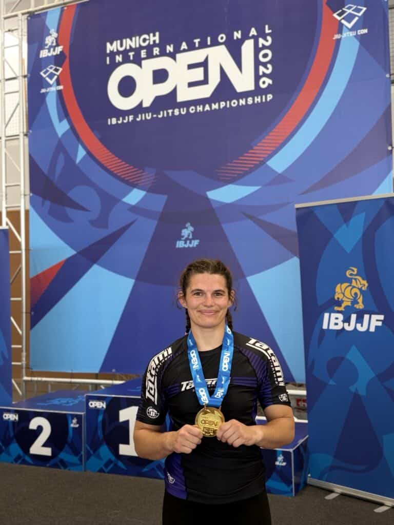 Bernadette Marsano mit Goldmedaille vor dem Banner der Munich International Open 2026